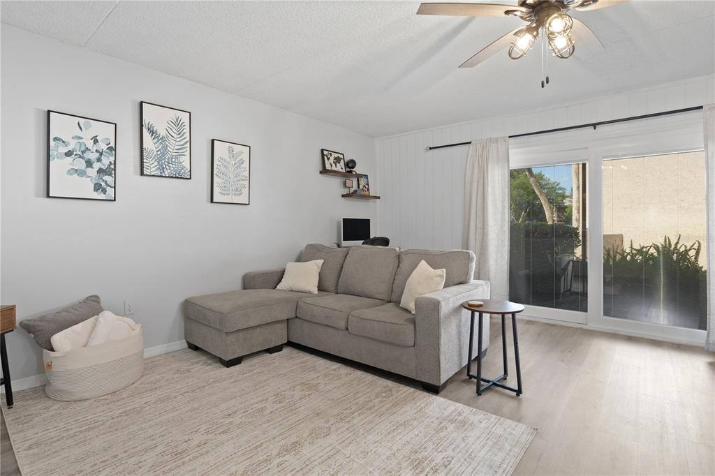 A living room features a gray sectional sofa, a rug, and sliding glass patio doors — 1154 PASEO DEL SOL UNIT B, CASSELBERRY, FL