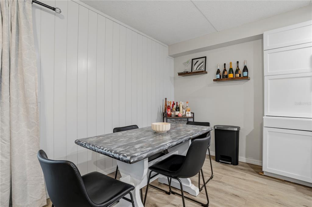 A dining area features a faux-finished table, black chairs, a bar cart, and wall shelving — 1154 PASEO DEL SOL UNIT B, CASSELBERRY, FL