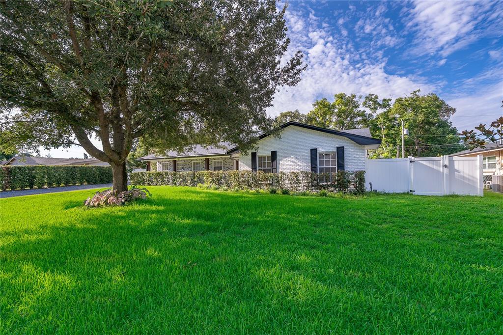 A white brick house with black shutters sits behind a large tree and lawn — 2462 CAROLTON ROAD, MAITLAND, FL