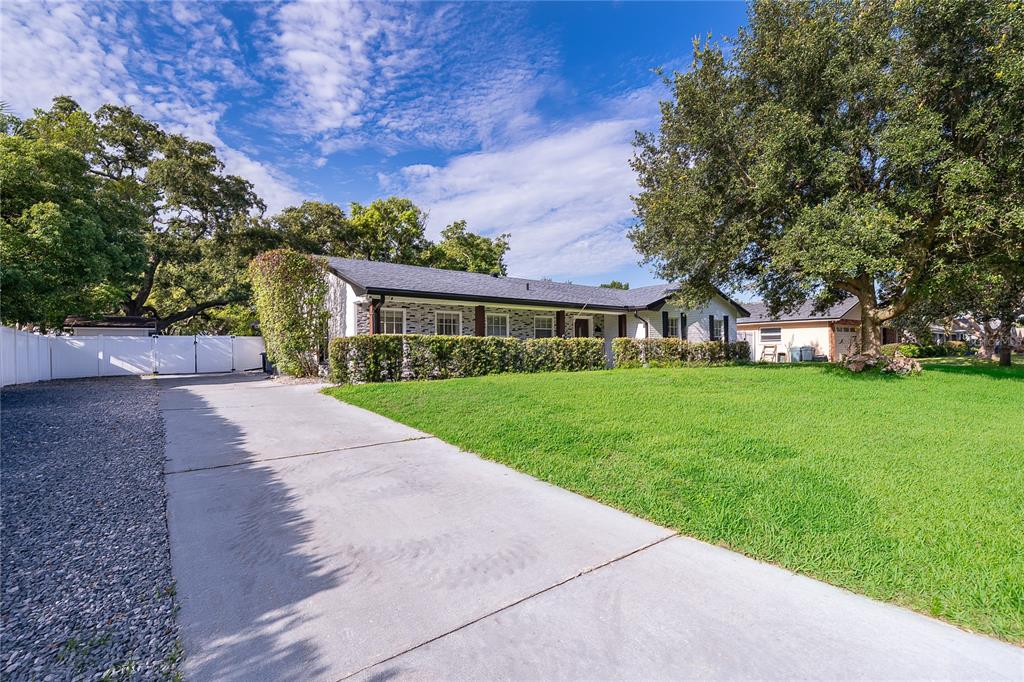 A single-story house with a white brick exterior, a concrete driveway, and a large lawn — 2462 CAROLTON ROAD, MAITLAND, FL