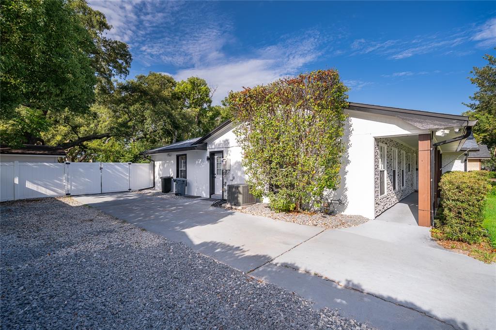 A white house with a concrete driveway, gravel area, and a covered side entrance — 2462 CAROLTON ROAD, MAITLAND, FL