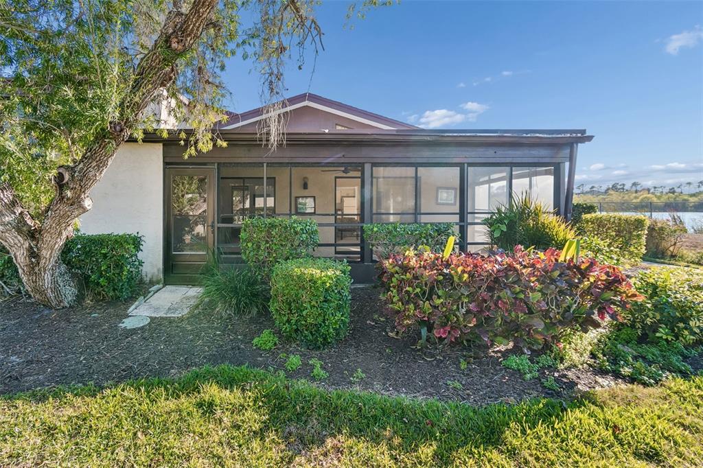 A screened-in patio overlooks a lake with surrounding landscaping and a large tree — 5400 34TH STREET W UNIT D16, BRADENTON, FL