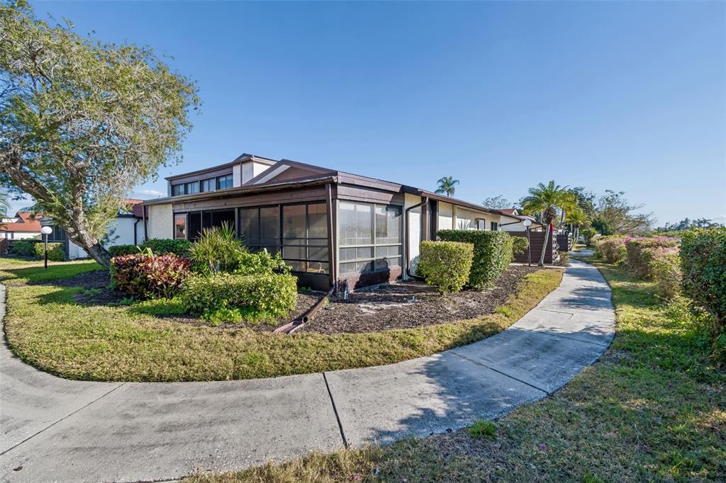 A single-story building with a screened-in porch and a concrete walkway surrounded by landscaping — 5400 34TH STREET W UNIT D16, BRADENTON, FL