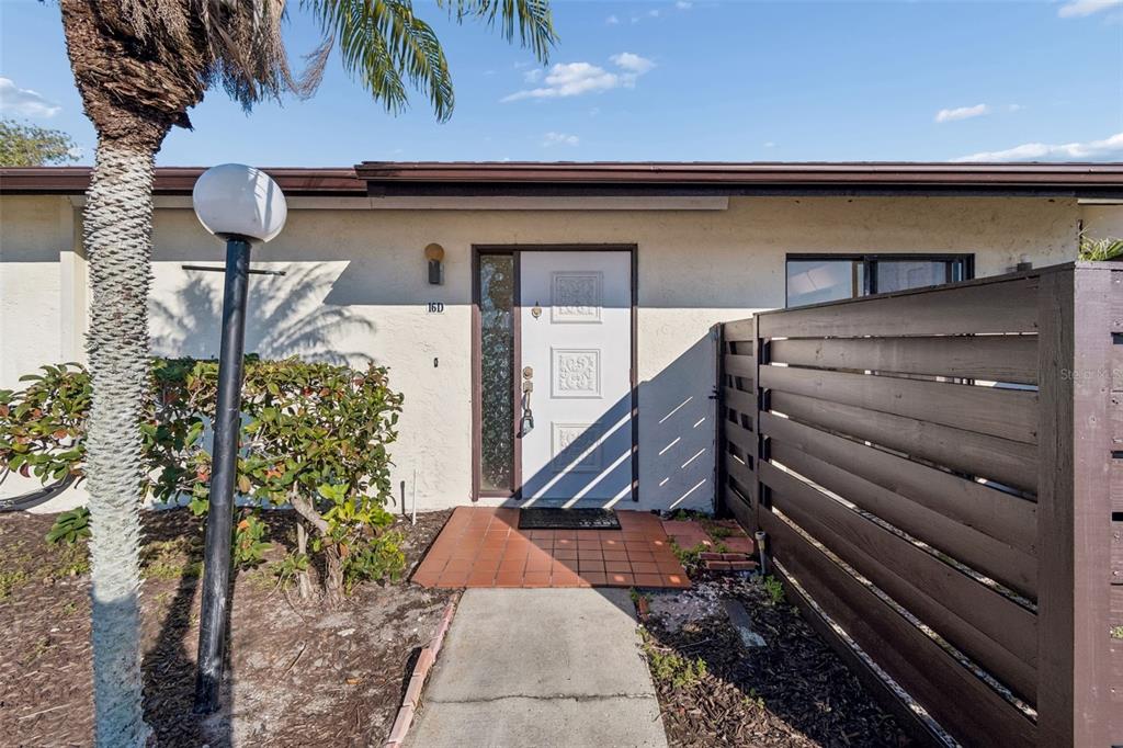 A concrete walkway leads to the front entrance of a single-story home with a fence — 5400 34TH STREET W UNIT D16, BRADENTON, FL