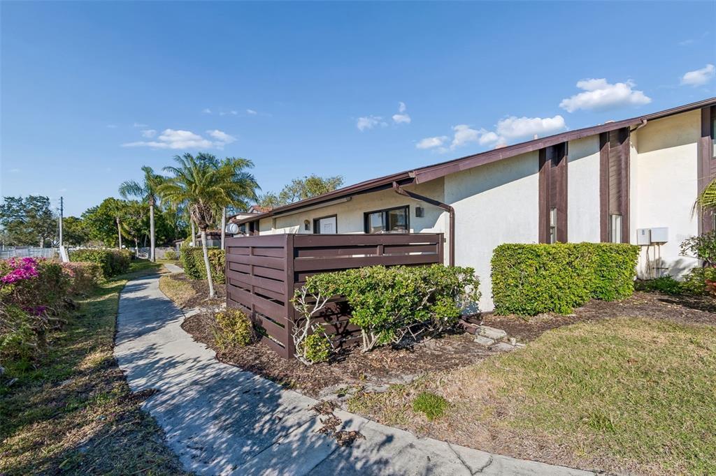 A concrete walkway leads past a brown privacy fence and a stucco exterior wall — 5400 34TH STREET W UNIT D16, BRADENTON, FL