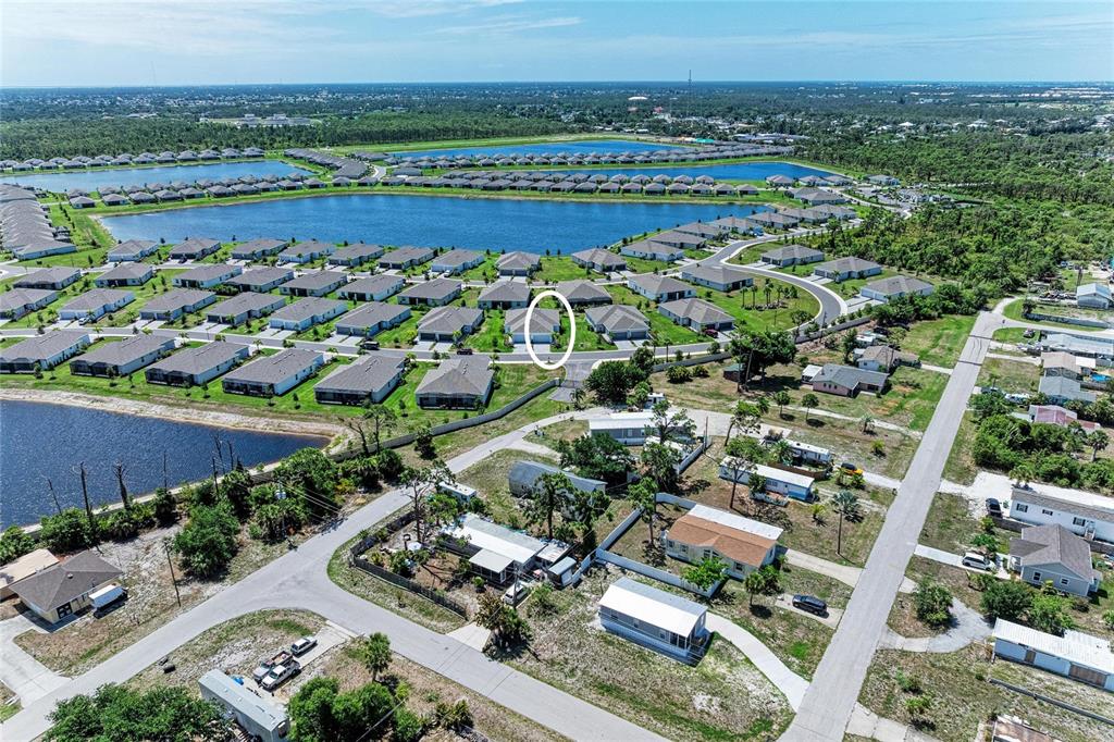 An aerial view shows a residential neighborhood with houses, lakes, and a gated entrance — 8682 SEASALT LOOP, ENGLEWOOD, FL