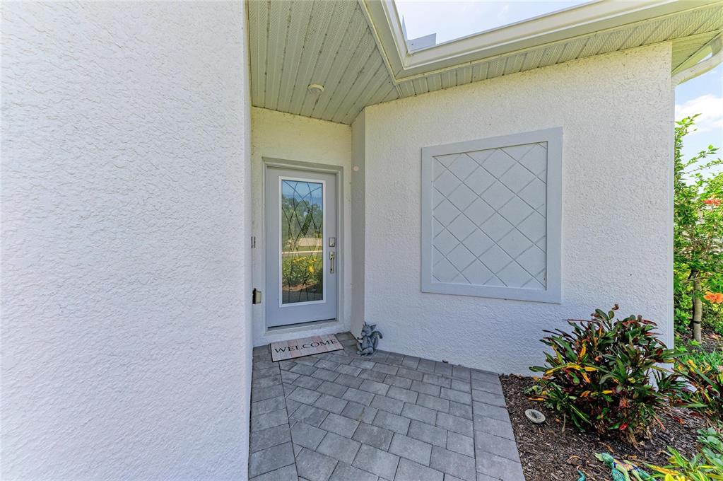 A front entryway features a light gray door with glass panels and a paved porch — 8682 SEASALT LOOP, ENGLEWOOD, FL