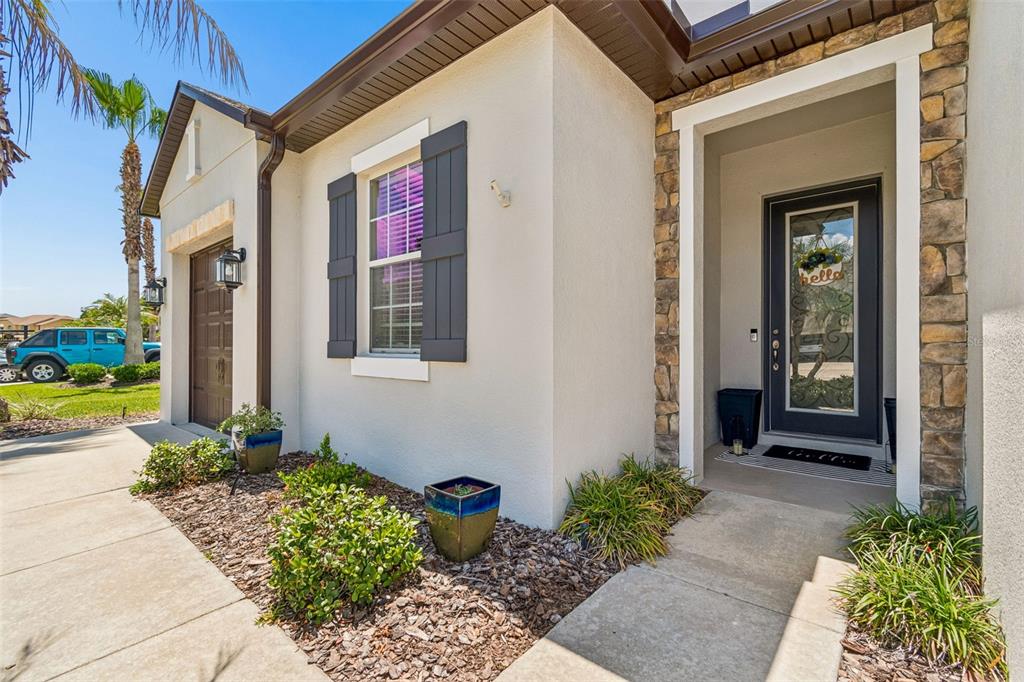 The exterior of a house features a stone-accented entryway, a dark front door, and shutters — 4123 WINDCREST DRIVE, WESLEY CHAPEL, FL