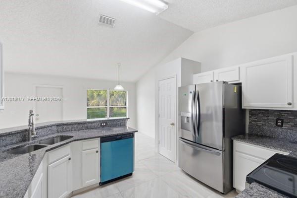 A kitchen with white cabinets, granite countertops, stainless steel appliances, and light tile flooring — 7608 Deland Ave, Fort Pierce FL 34951, FORT PIERCE, FL