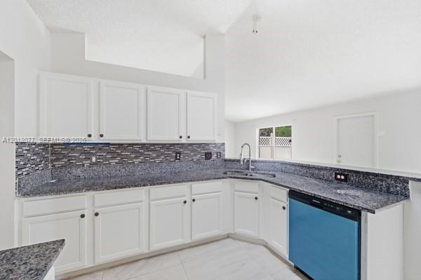 A kitchen features white cabinets, dark granite countertops, a tiled backsplash, and a blue dishwasher — 7608 Deland Ave, Fort Pierce FL 34951, FORT PIERCE, FL