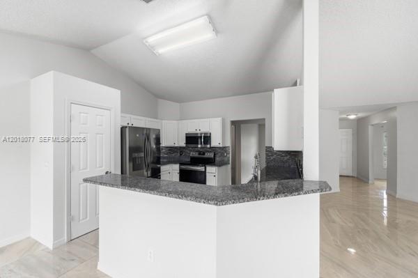 A kitchen features white cabinetry, granite countertops, stainless steel appliances, and a breakfast bar — 7608 Deland Ave, Fort Pierce FL 34951, FORT PIERCE, FL