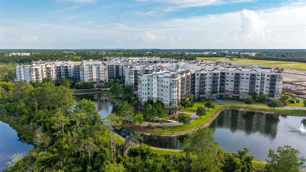 An aerial view of a large multi-story apartment complex surrounded by trees and ponds — 14501 GROVE RESORT AVENUE UNIT 1527, WINTER GARDEN, FL