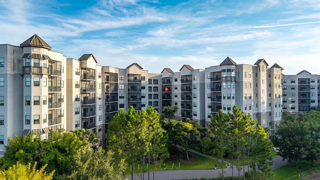 An exterior view of a multi-story apartment complex with balconies and surrounding trees — 14501 GROVE RESORT AVENUE UNIT 1527, WINTER GARDEN, FL