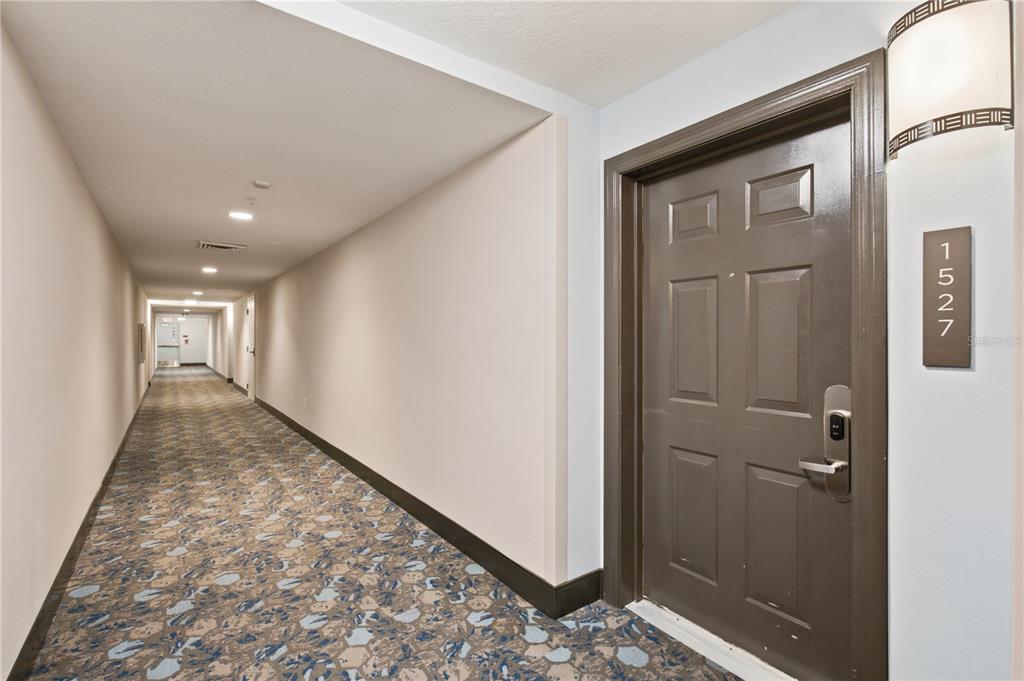 A long carpeted hallway features a brown door labeled 1527 with a wall-mounted light fixture — 14501 GROVE RESORT AVENUE UNIT 1527, WINTER GARDEN, FL