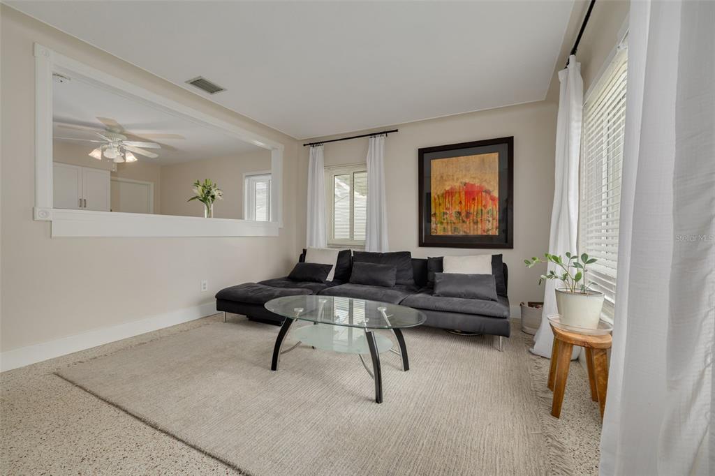 A living room features a dark sectional sofa, a glass coffee table, and a pass-through window — 531 75TH AVENUE N, ST PETERSBURG, FL