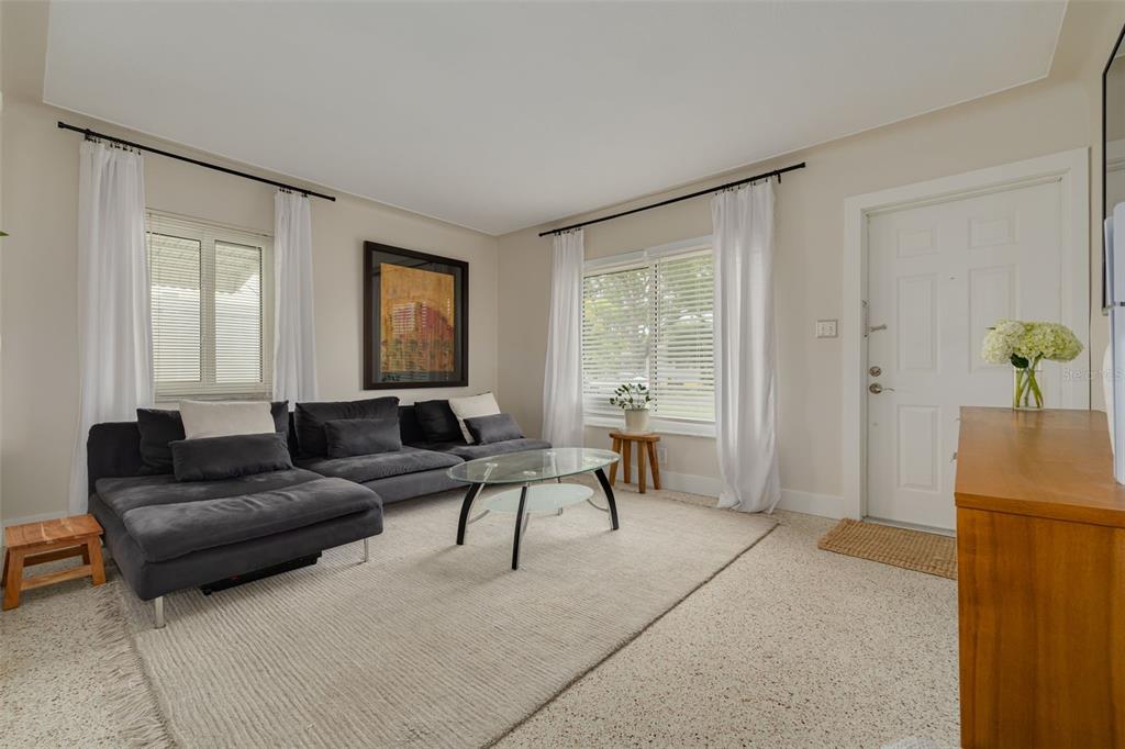 A living room features a dark gray sectional sofa, glass coffee table, and white curtains — 531 75TH AVENUE N, ST PETERSBURG, FL