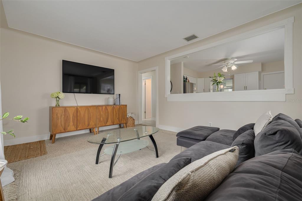 A living room features a grey sectional sofa, a glass coffee table, and a media console — 531 75TH AVENUE N, ST PETERSBURG, FL