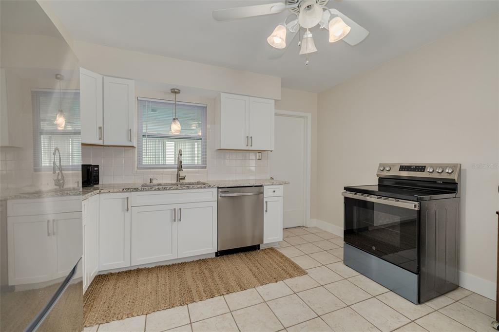 A kitchen with white cabinets, granite countertops, stainless steel appliances, and light-colored tile flooring — 531 75TH AVENUE N, ST PETERSBURG, FL