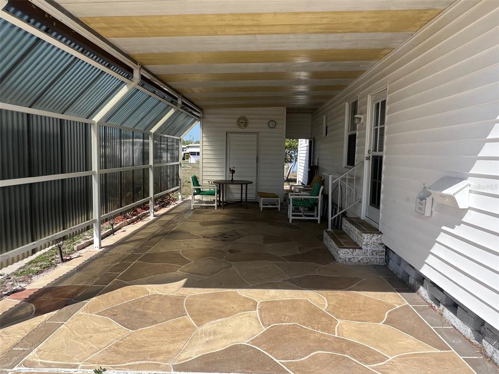 A covered patio features a stamped concrete floor, white siding, and a metal screen enclosure — 13225 101ST STREET UNIT 168, LARGO, FL