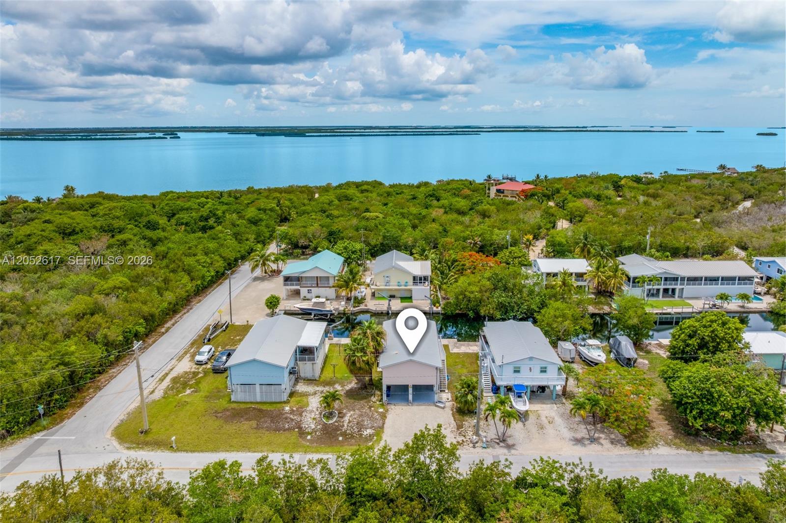 An aerial view shows a light-colored house with a canal and water in the background — LOWER KEYS, FL