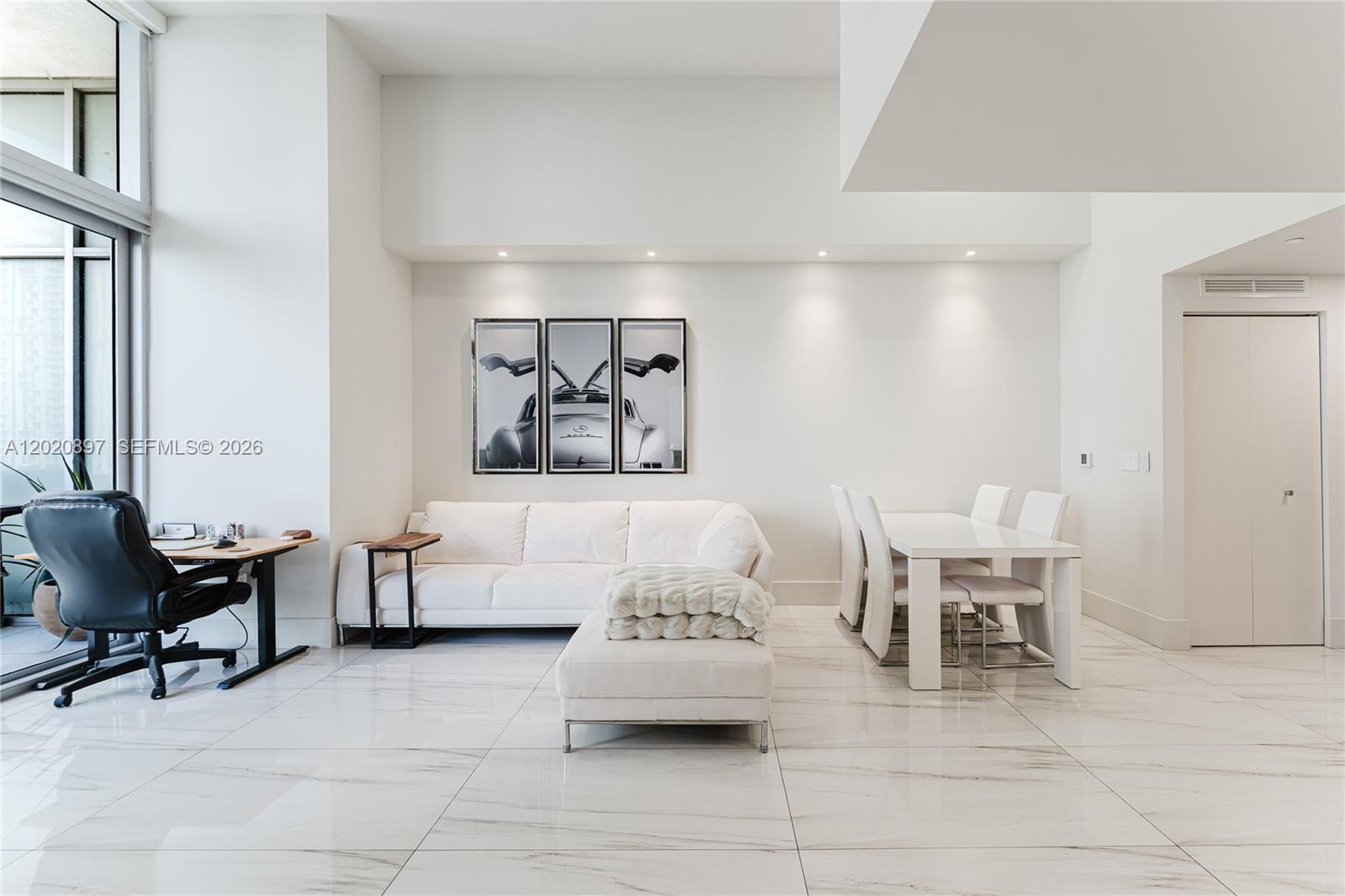 A bright, modern living and dining area features white tile floors and minimalist furniture — 488 NE 18th St # 1205, Miami FL 33132, MIAMI, FL
