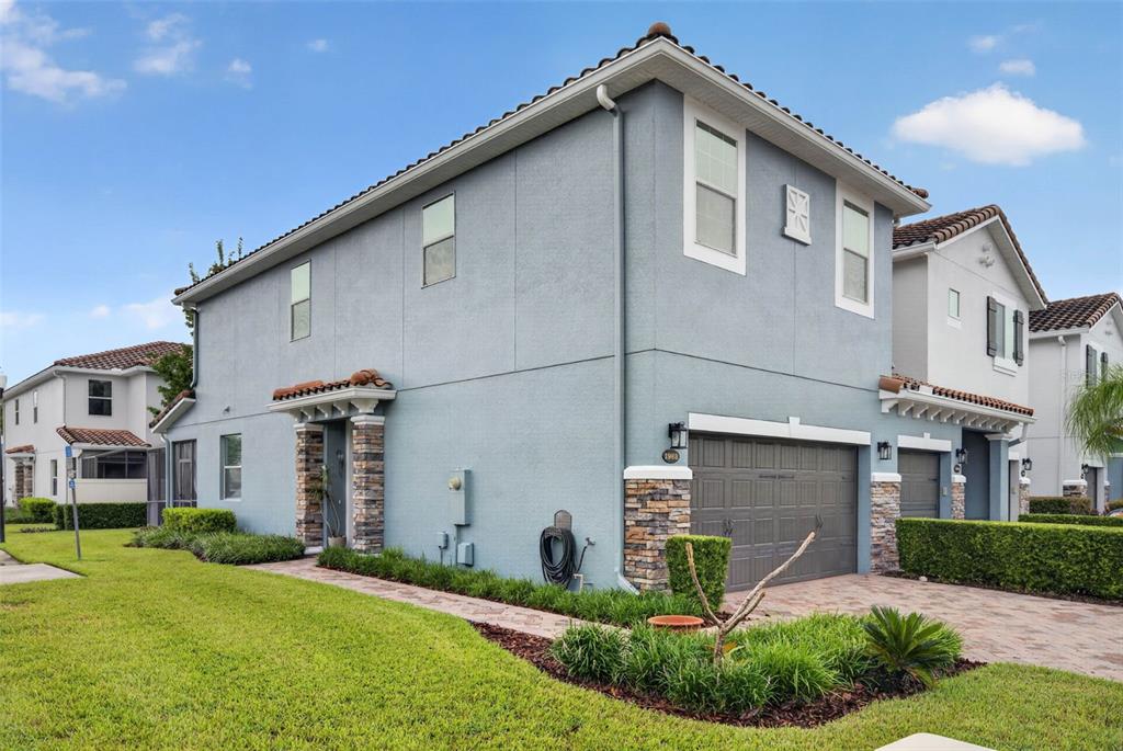 A two-story house with a gray stucco exterior, stone accents, and an attached garage — 1988 SAFFRON COURT, OVIEDO, FL