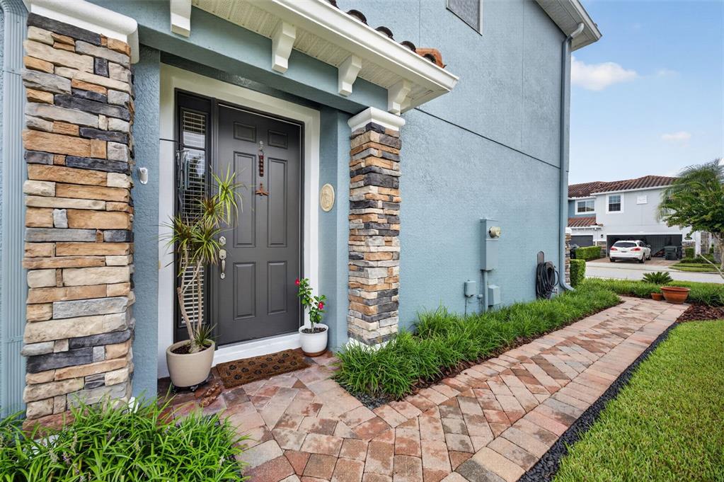 A front entrance with a dark door, stone columns, and a paved walkway — 1988 SAFFRON COURT, OVIEDO, FL