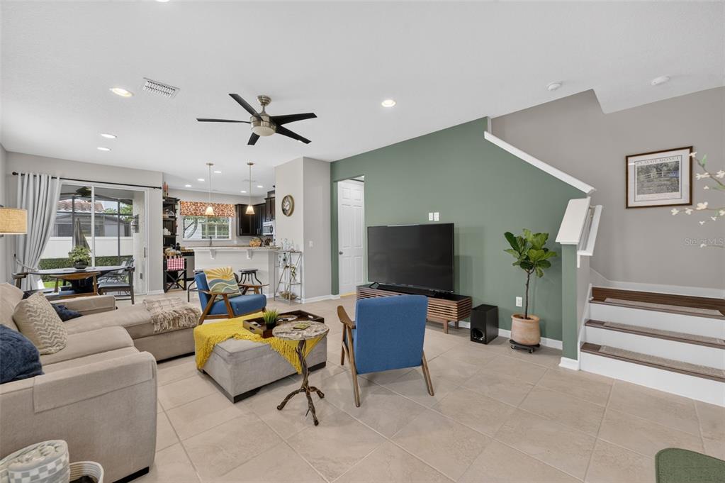 A living room features a green accent wall, a television, blue chairs, and stairs — 1988 SAFFRON COURT, OVIEDO, FL