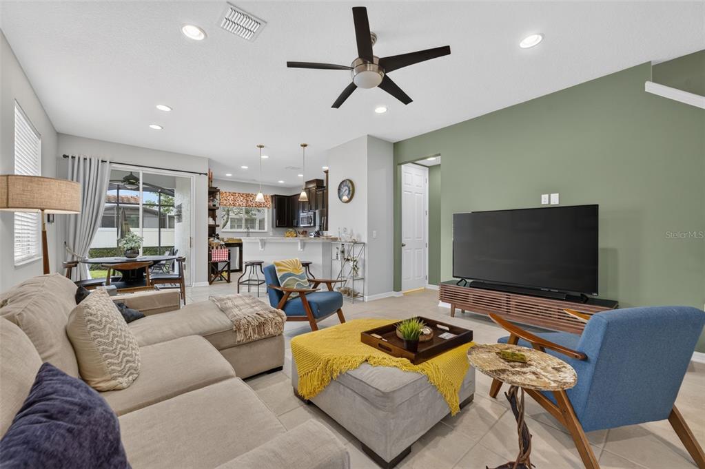 A living room features a beige sectional, two blue armchairs, and a green accent wall — 1988 SAFFRON COURT, OVIEDO, FL