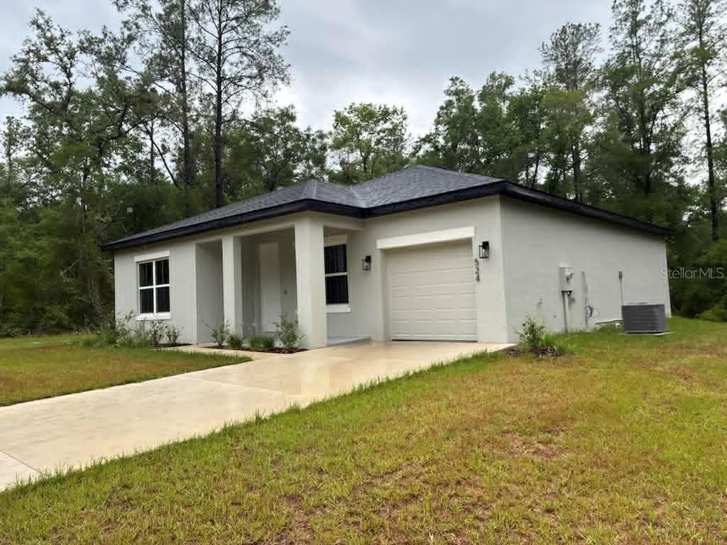 A single-story house with a light-colored stucco exterior, a one-car garage, and a concrete driveway — 524 E AVONDALE DRIVE, DUNNELLON, FL