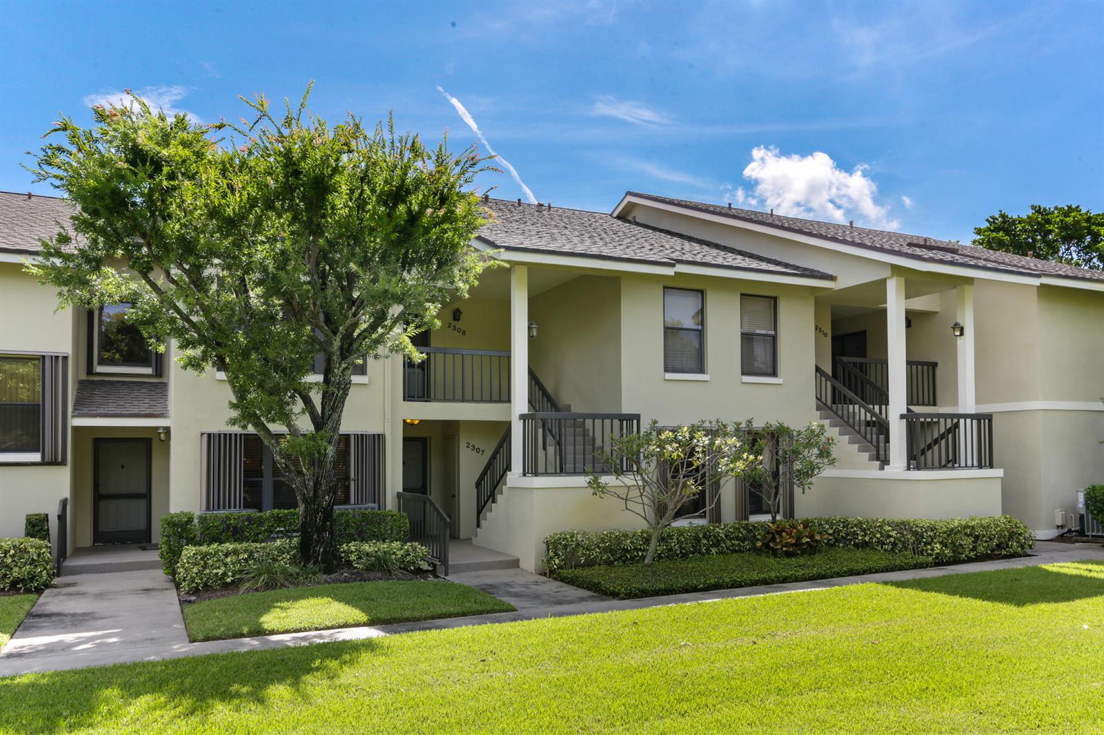A two-story apartment building with light green stucco walls, dark railings, and a landscaped lawn — 2306 FAIRWAY Drive S, Jupiter FL 33477, JUPITER, FL