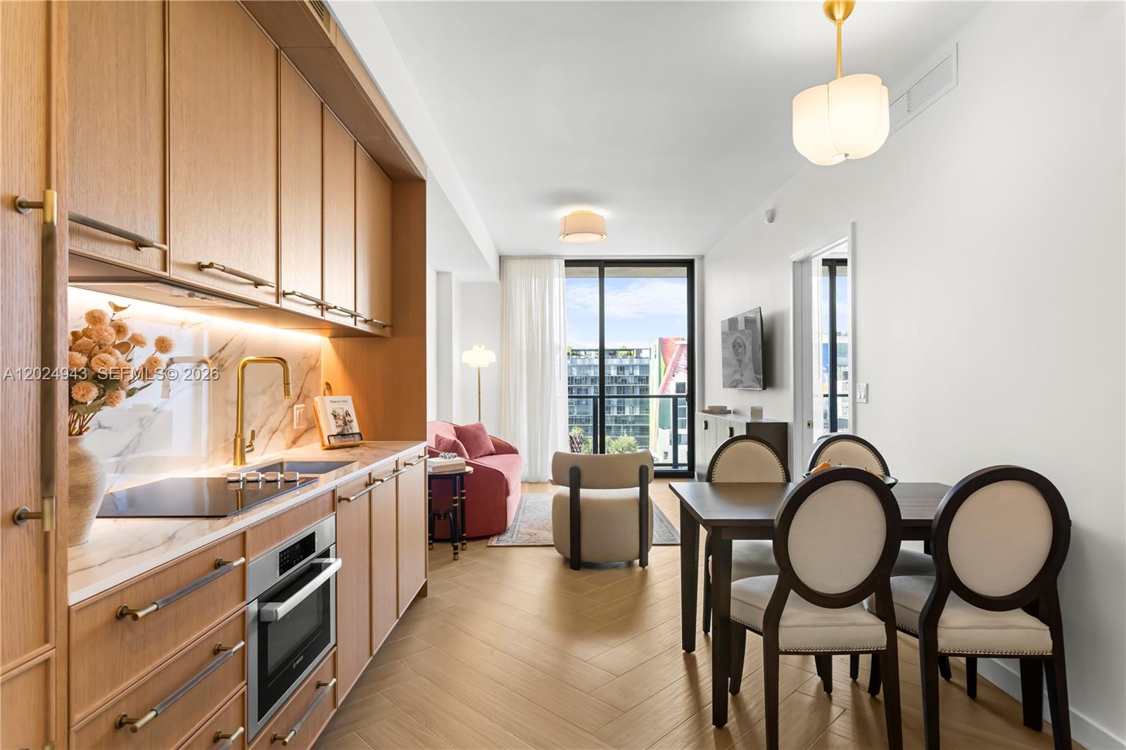 A modern kitchen and dining area with light wood cabinets, herringbone floors, and balcony access — 2700 NW 2nd Ave # 710, Miami FL 33127, MIAMI, FL