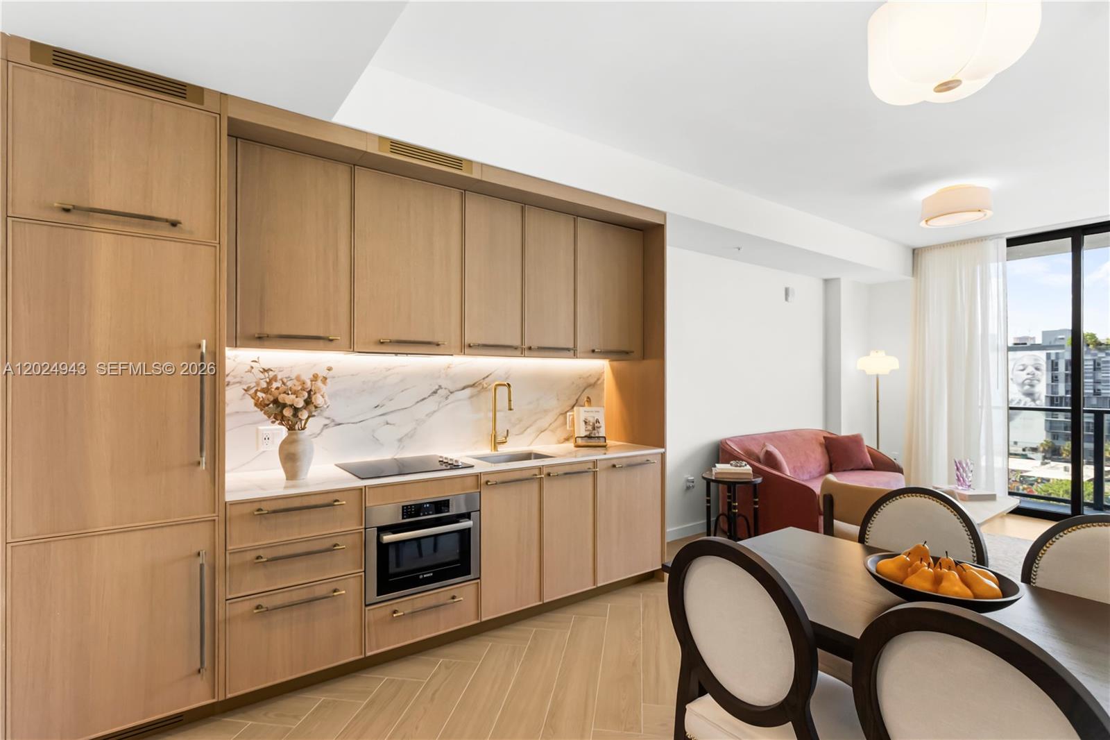 A modern kitchen with light wood cabinetry and marble backsplash opens into a dining area — 2700 NW 2nd Ave # 710, Miami FL 33127, MIAMI, FL