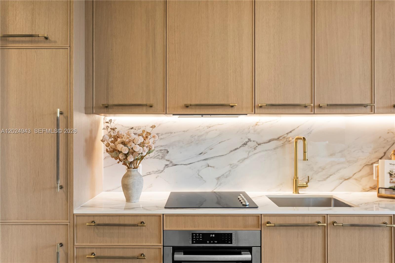A modern kitchen features light wood cabinets, a marble backsplash, and gold hardware — 2700 NW 2nd Ave # 710, Miami FL 33127, MIAMI, FL