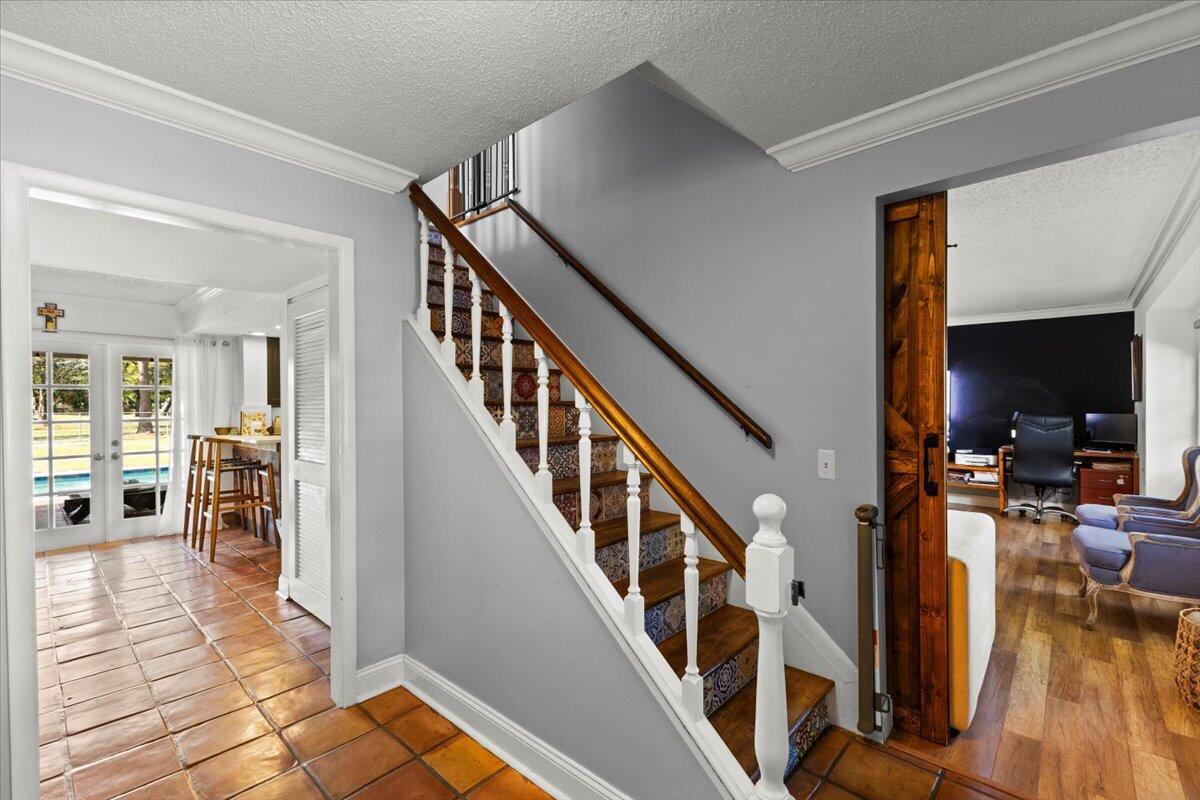 A staircase with patterned risers and a wooden handrail sits between a tiled entryway and office — 3179 Hoylake Road, Lake Worth FL 33467, LAKE WORTH, FL