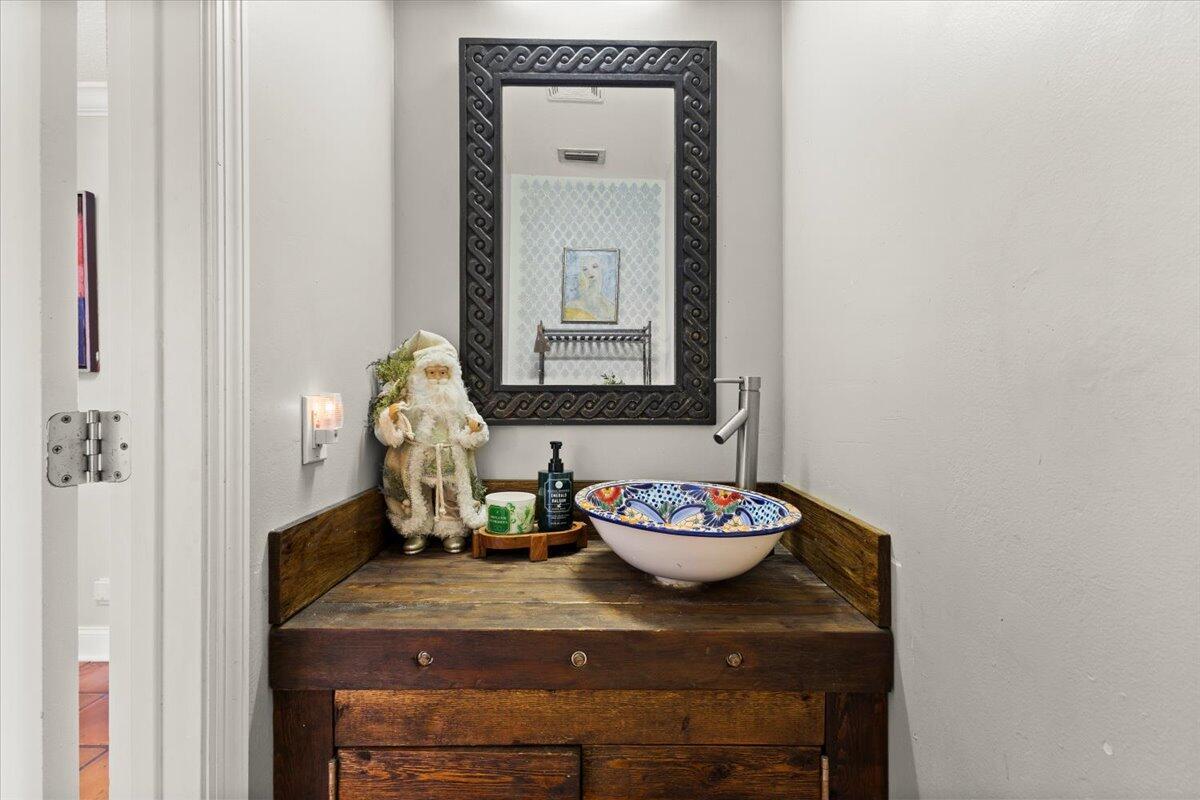 A rustic wooden vanity with a colorful vessel sink sits below a decorative framed mirror — 3179 Hoylake Road, Lake Worth FL 33467, LAKE WORTH, FL