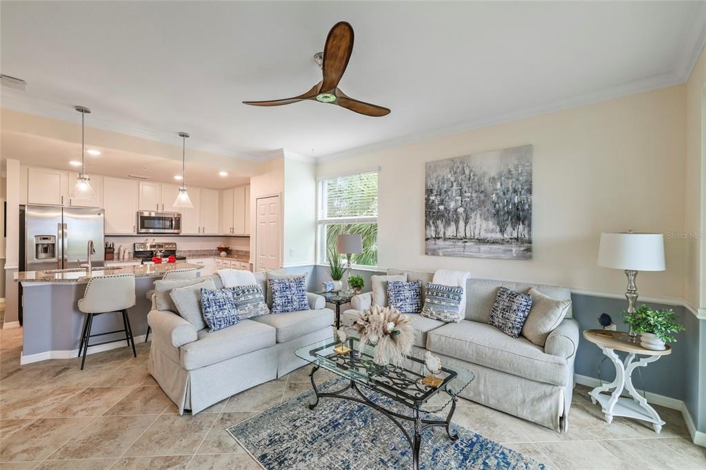 A living room with a sofa, glass coffee table, and an open kitchen with island seating — 14091 HERITAGE LANDING BOULEVARD UNIT 121, PUNTA GORDA, FL