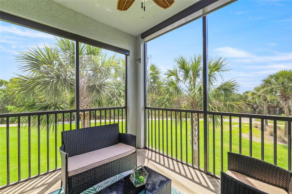 A screened-in balcony features wicker furniture and views of palm trees and a grassy lawn — 14091 HERITAGE LANDING BOULEVARD UNIT 121, PUNTA GORDA, FL
