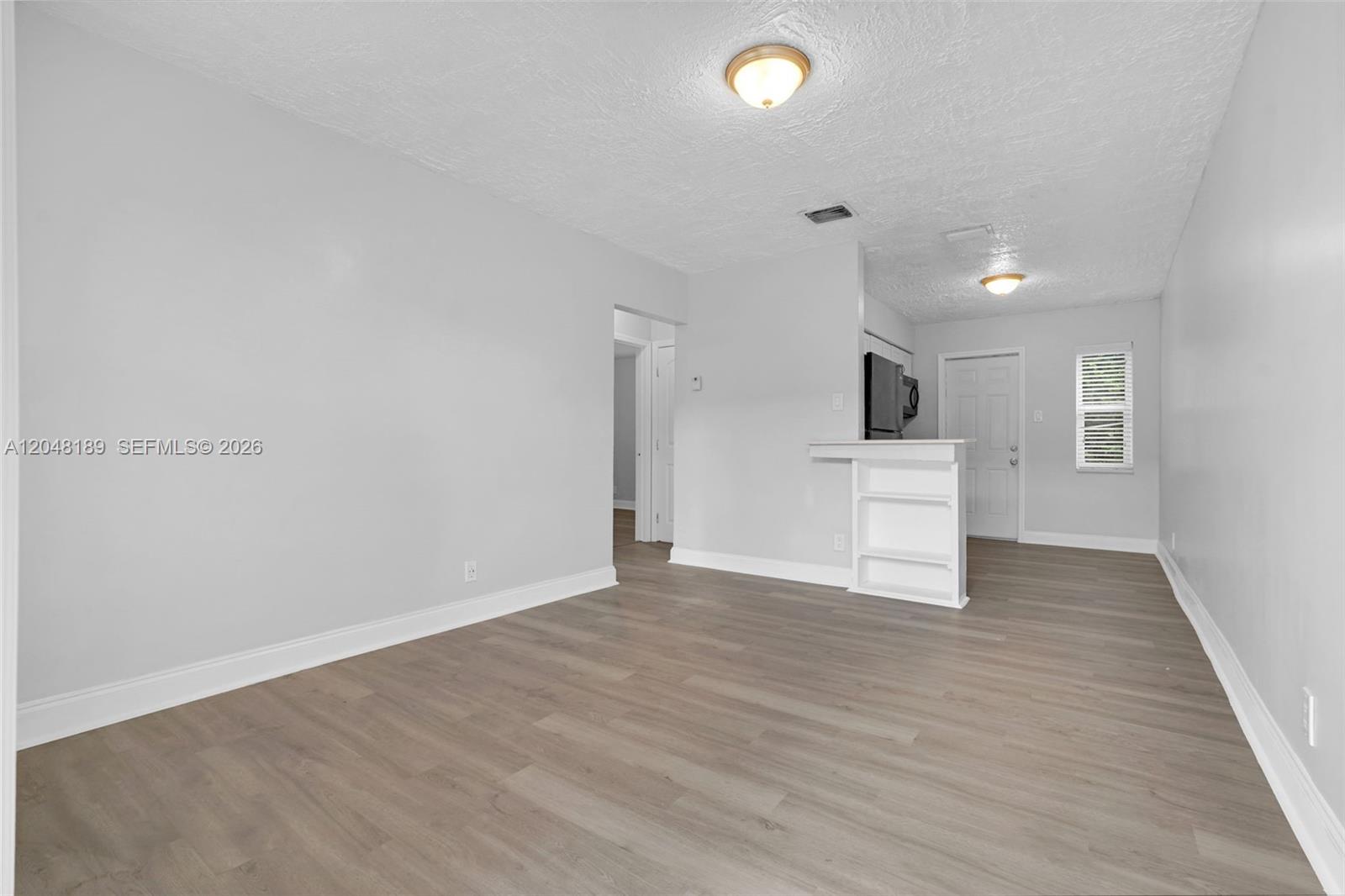 This living room features light gray walls, wood-look flooring, and a small white partition wall — 746 SW 4th St # 1, Dania Beach FL 33004, DANIA BEACH, FL