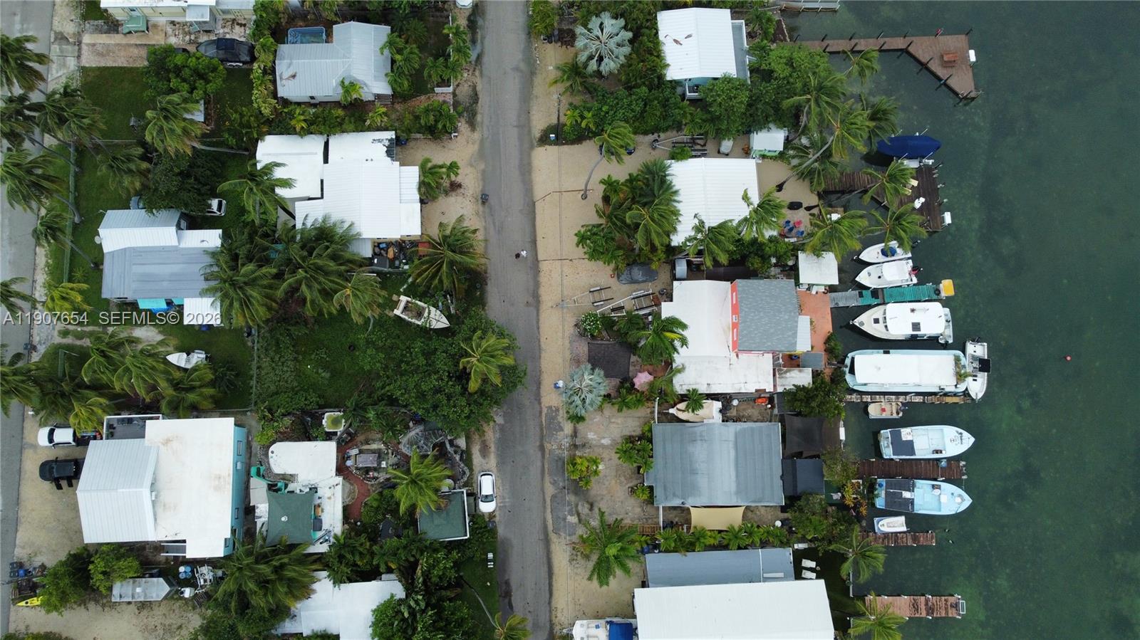 An aerial view shows houses along a road with private docks and boats in water — 77 S Conch Ave, Marathon FL 33050, MARATHON, FL