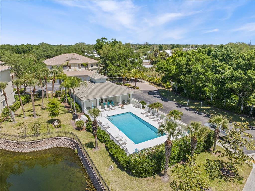 An aerial view shows a swimming pool and clubhouse next to a small pond — 300 GARDENS EDGE DRIVE UNIT 324, VENICE, FL