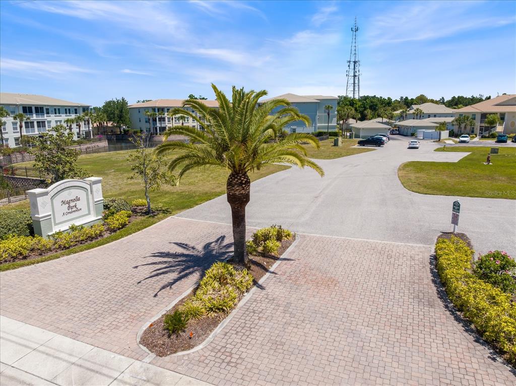 An exterior view shows the entrance to Magnolia Park Condominiums with a palm tree — 300 GARDENS EDGE DRIVE UNIT 324, VENICE, FL