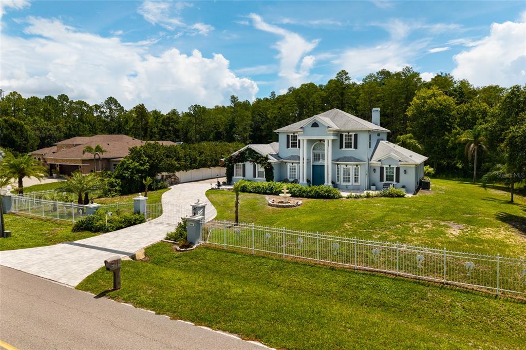 A two-story light blue house with a paved driveway and a white fence — 1436 ALTAMONT LANE, ODESSA, FL