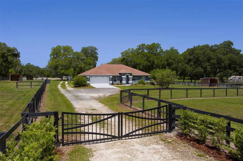 A single-story house with a gravel driveway and black metal fencing on a grassy lot — 8548 NW 115TH AVENUE, OCALA, FL