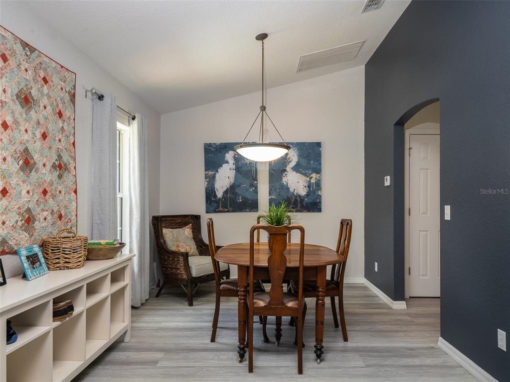 A dining area features a wooden table, chairs, a wicker armchair, and a dark accent wall — 8548 NW 115TH AVENUE, OCALA, FL