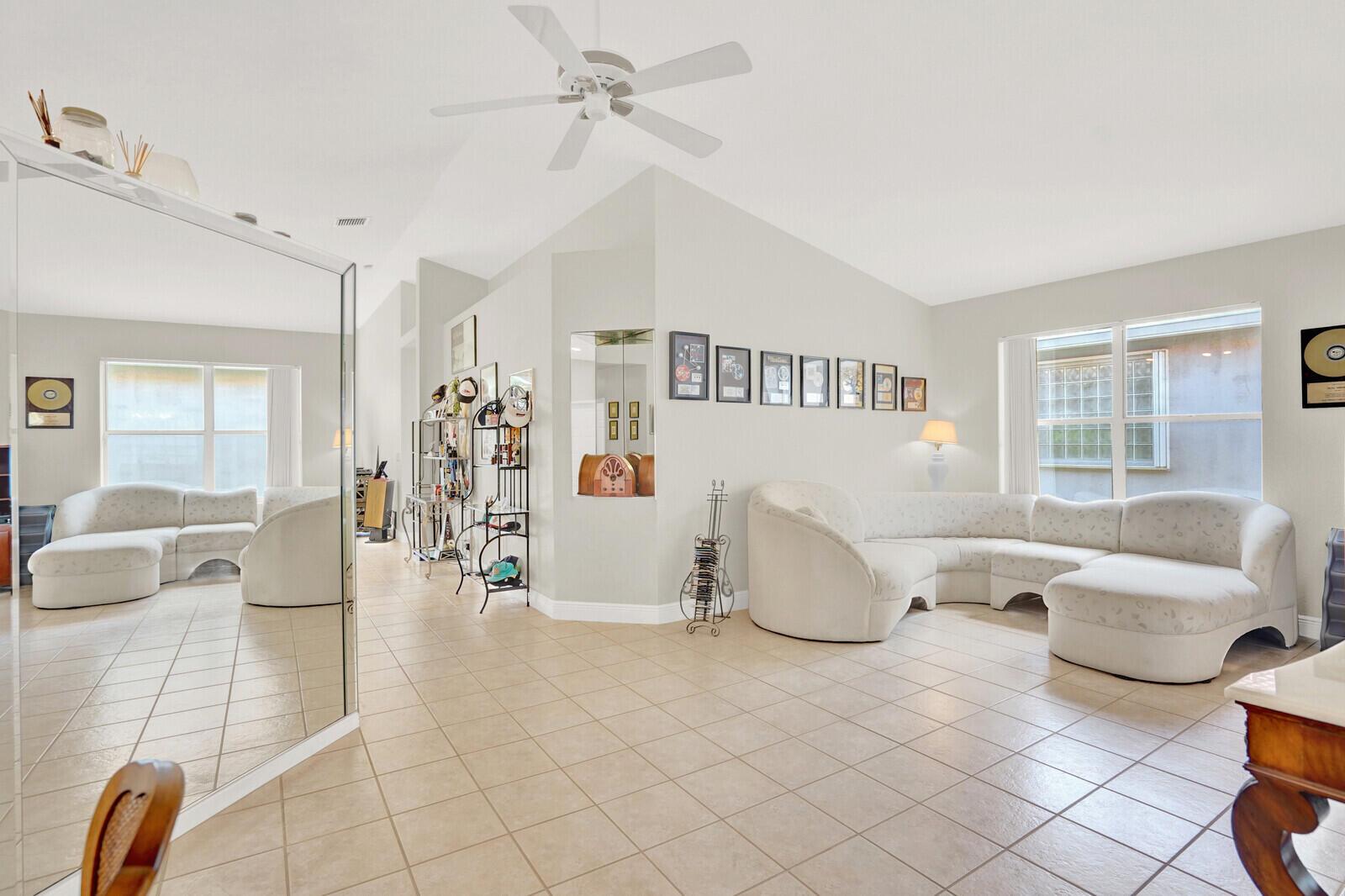 A living room features a large sectional sofa, tiled floors, and framed wall art — 7756 Cherry Blossom Way, Boynton Beach FL 33437, BOYNTON BEACH, FL