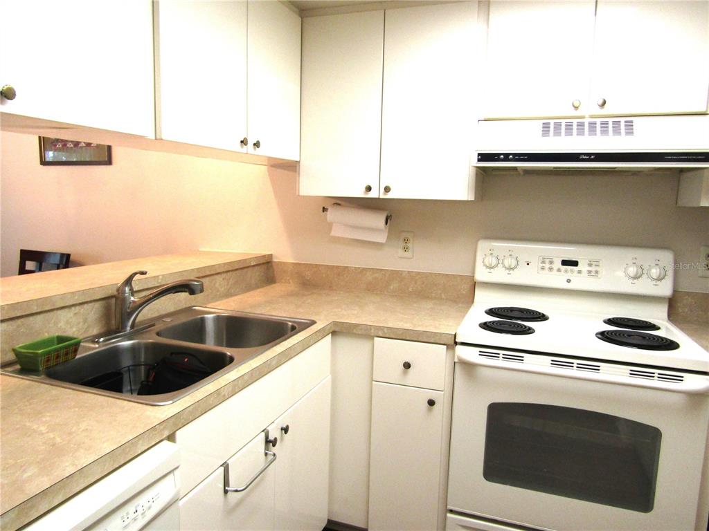 A kitchen features white cabinets, a double sink, and a white electric range — 4632 RINGWOOD MEADOW UNIT 28, SARASOTA, FL