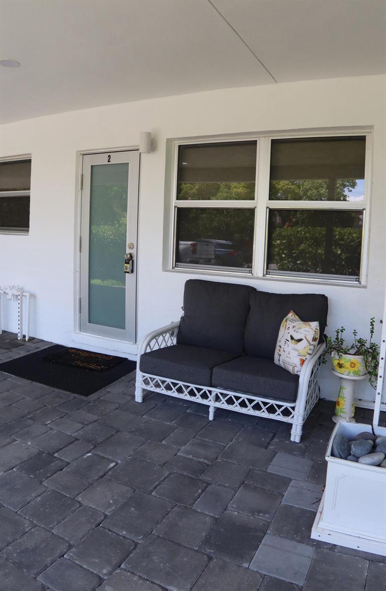 A white exterior wall features a door labeled 2, a window, and a patio sofa — 3408 Spring Street # 2, Pompano Beach FL 33062, POMPANO BEACH, FL