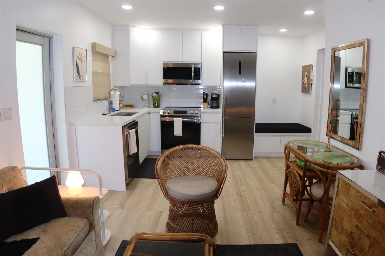 A kitchen with white cabinets, stainless steel appliances, and a small dining area with wicker chairs — 3408 Spring Street # 2, Pompano Beach FL 33062, POMPANO BEACH, FL