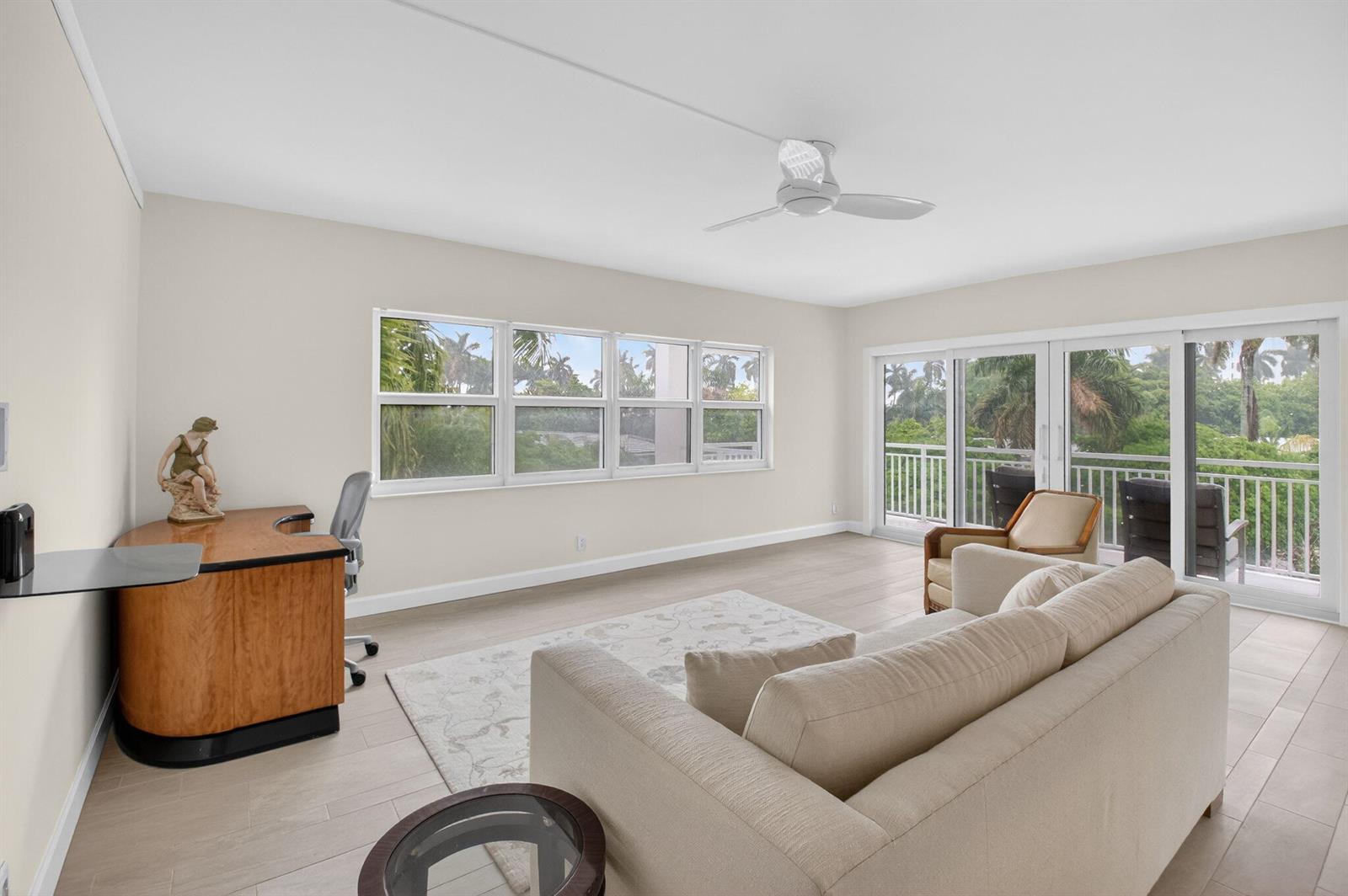 A living room with a desk, sofa, ceiling fan, and sliding doors leading to a balcony — 1000 Lowry Street # 3e, Delray Beach FL 33483, DELRAY BEACH, FL